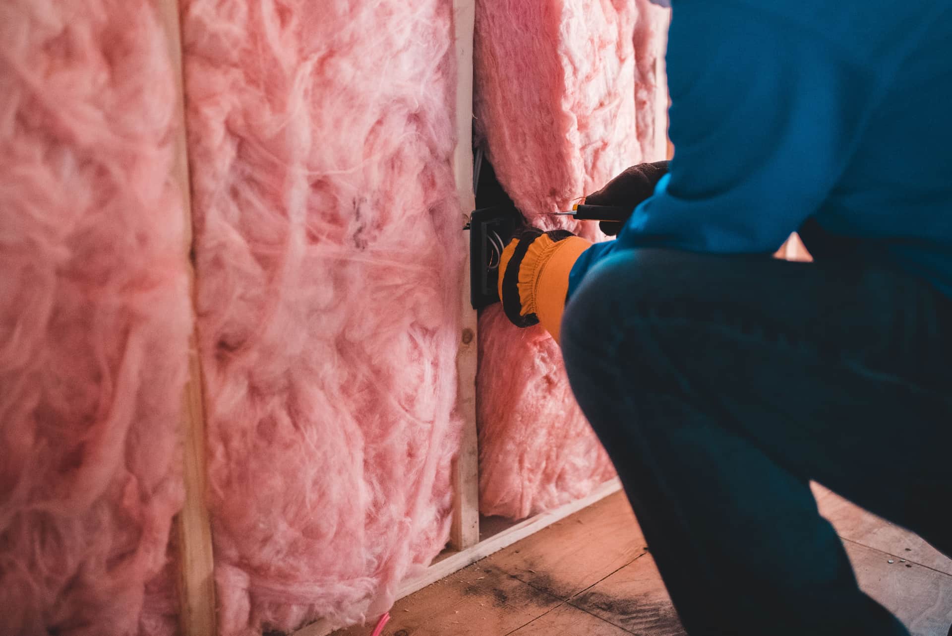A worker handling insulation material in a roof space