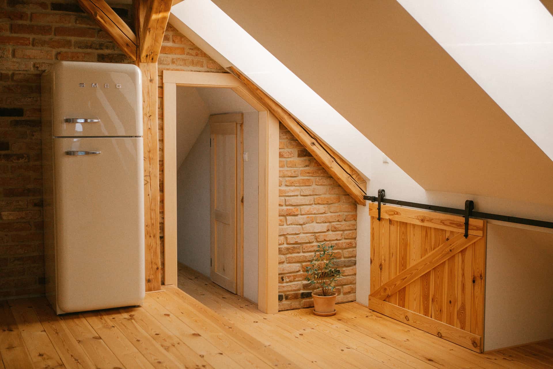 An attic space with exposed wooden roof beams seen from the loft floor