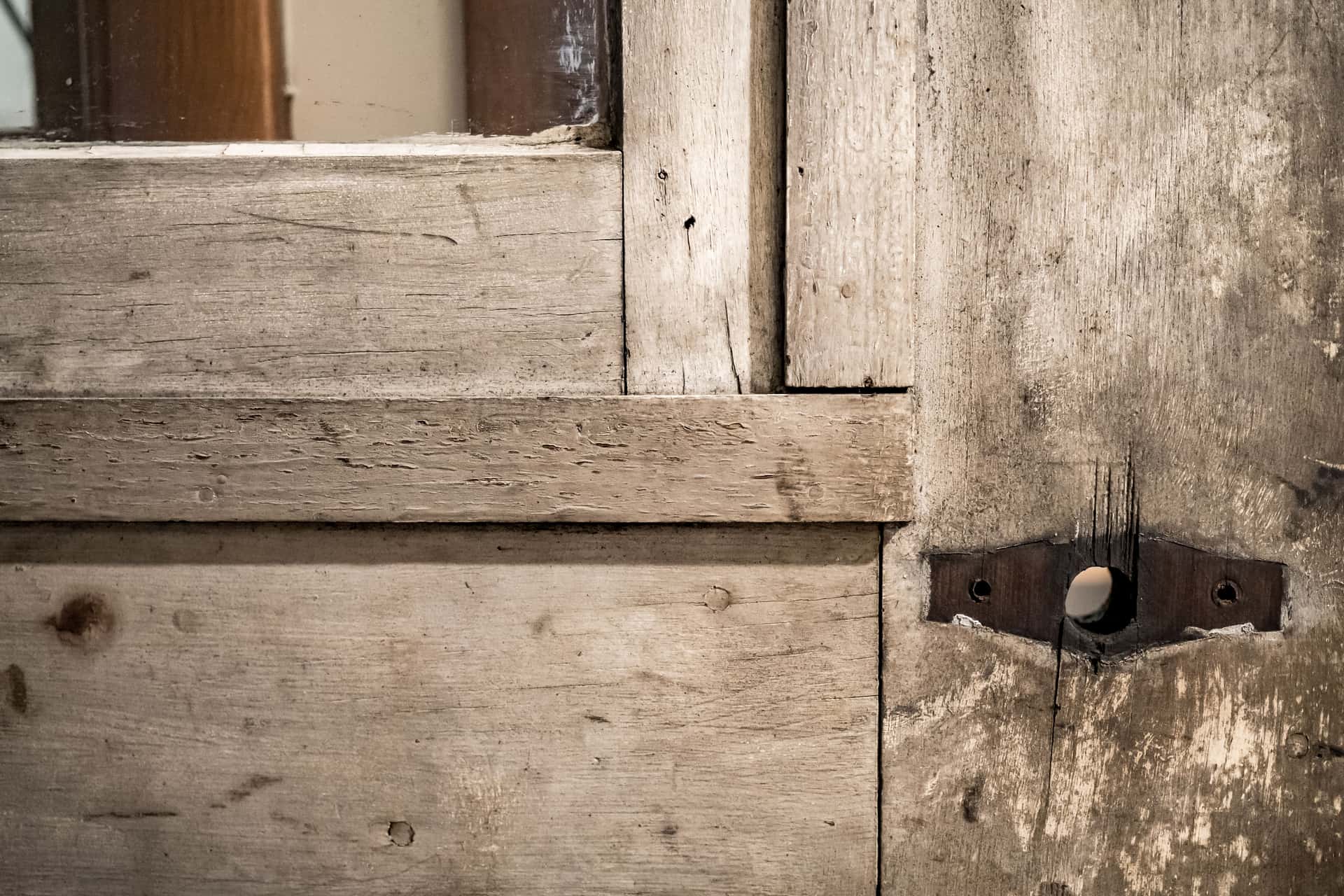 Close-up of an old weathered wooden door showing its joinery and original hardware
