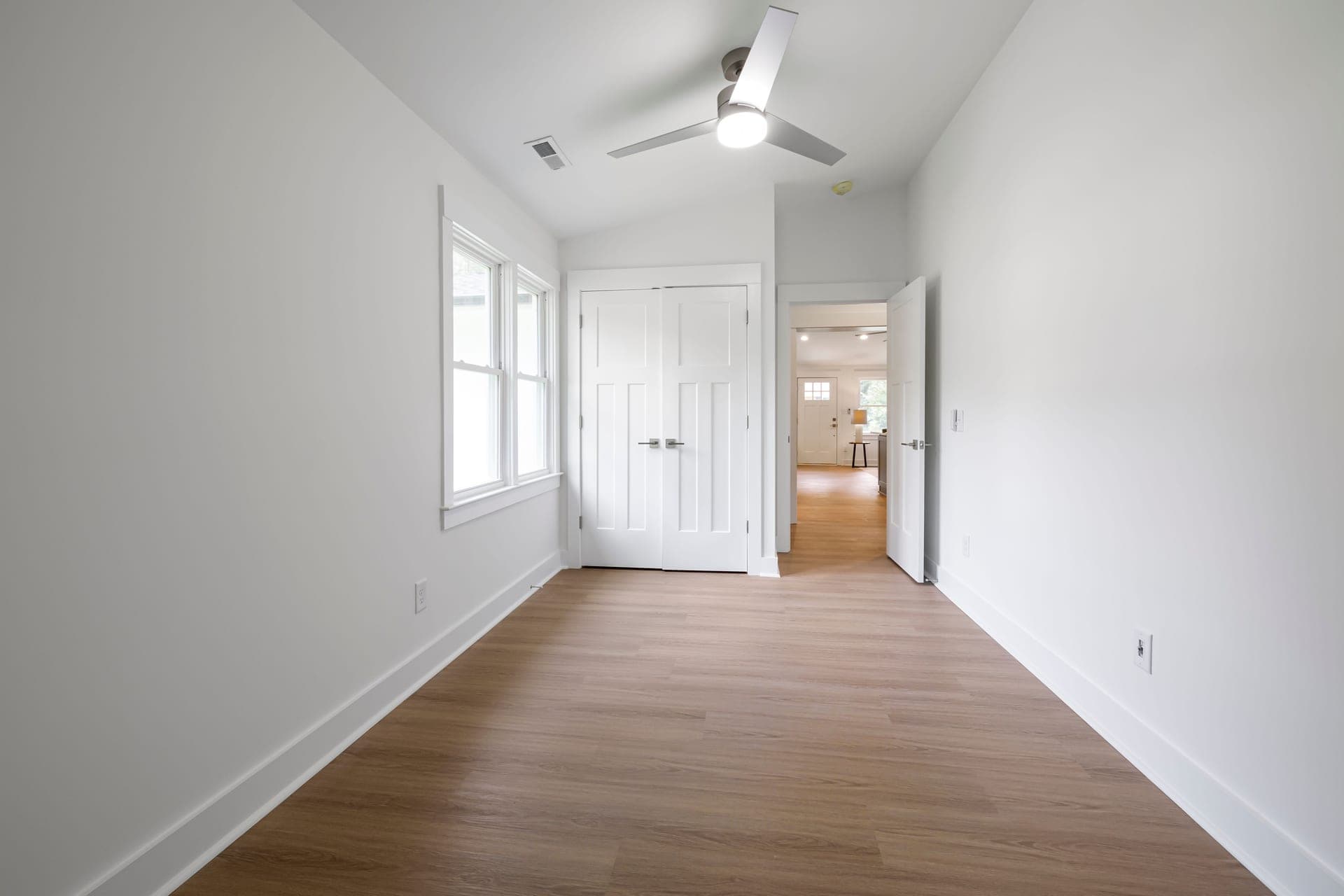 A minimalist bedroom with wood flooring and a closed interior door
