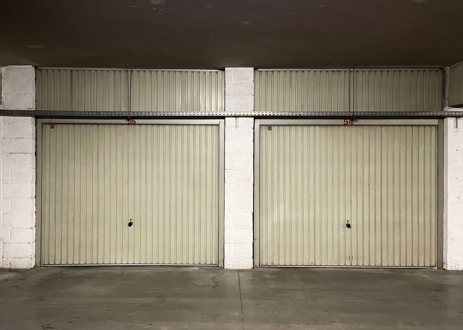 Daylight showing unevenly under a closed sectional garage door across a concrete slab