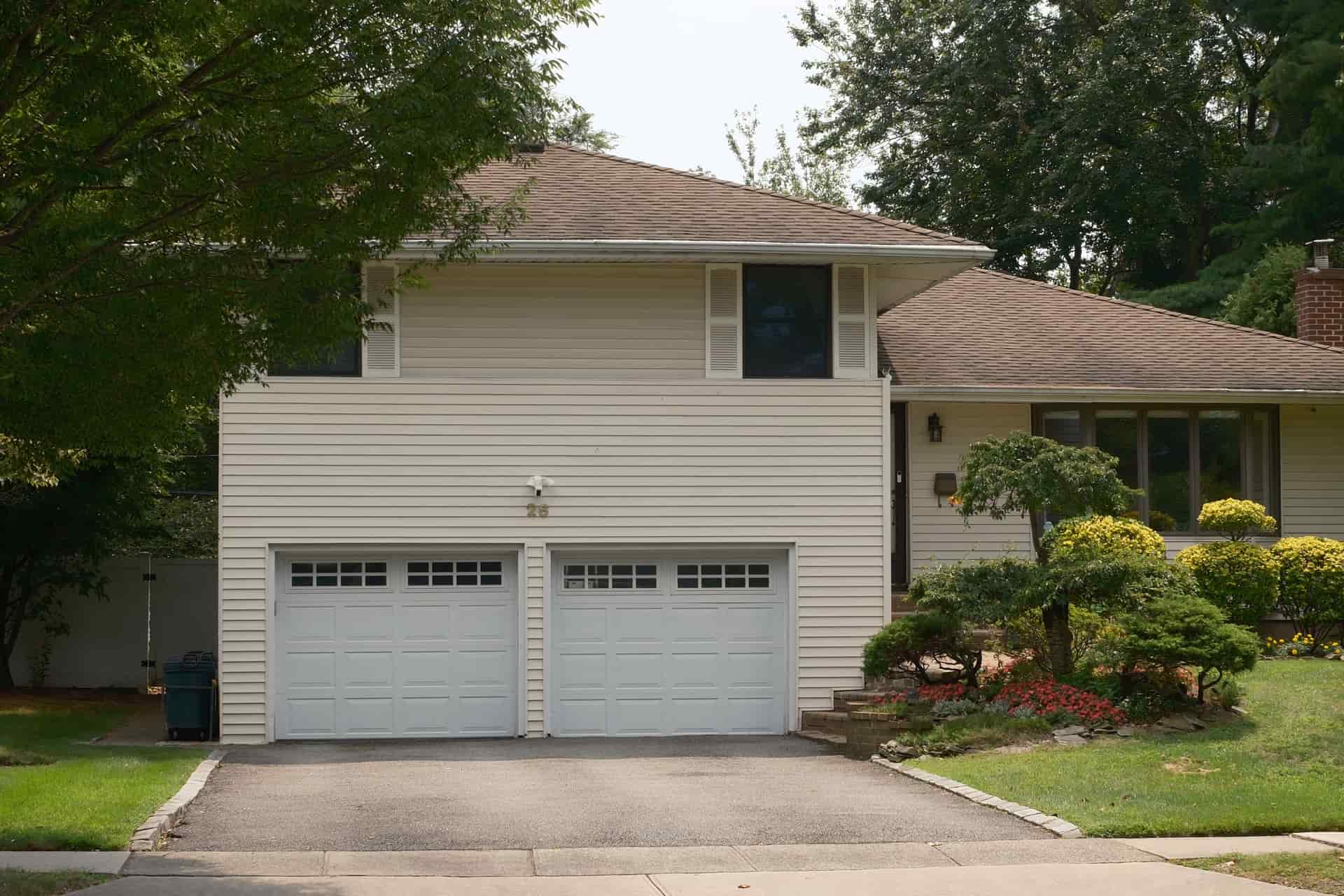 A suburban house with a double garage door seen from the driveway