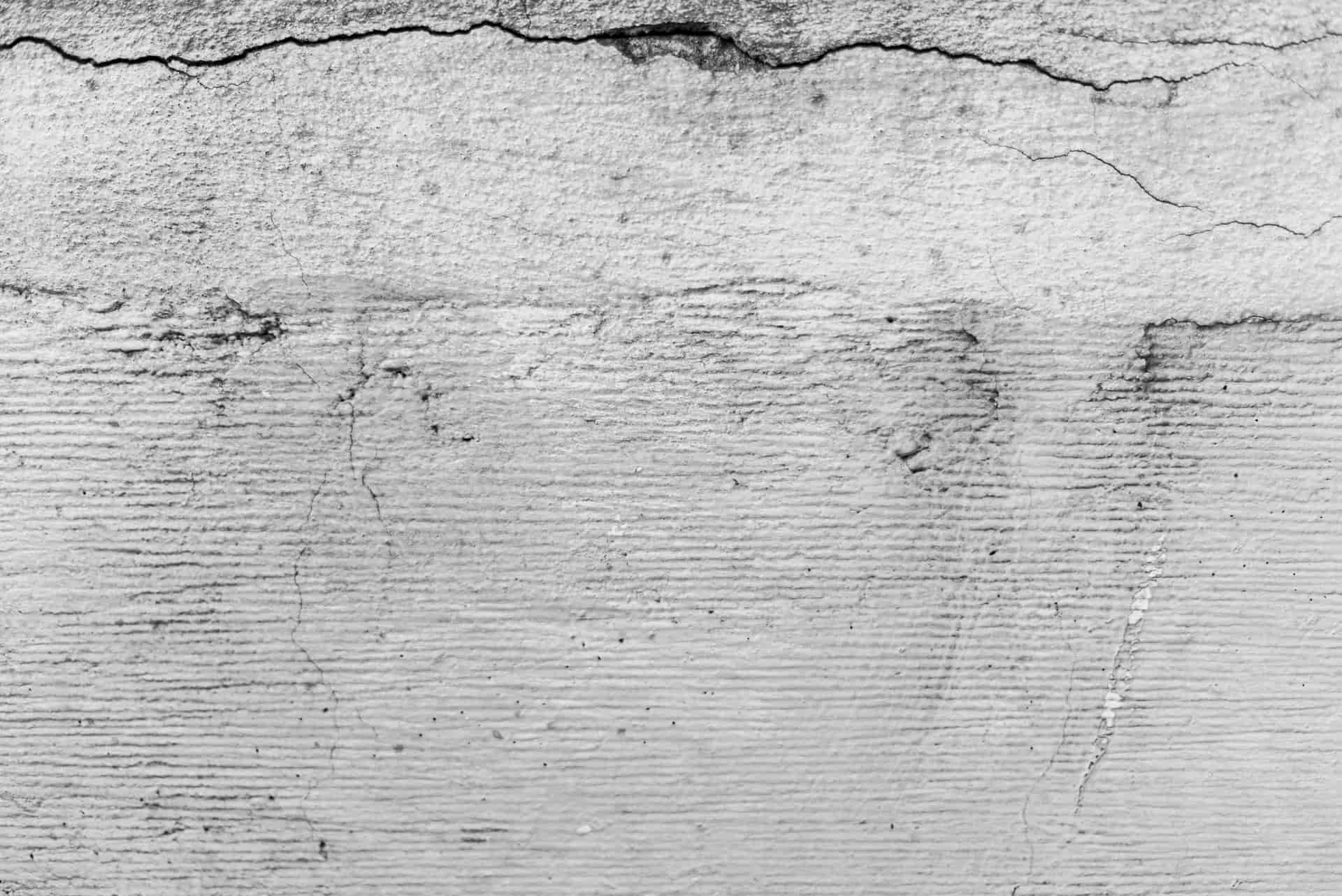 A worn concrete garage slab with a visible dip at the door opening, seen at floor level