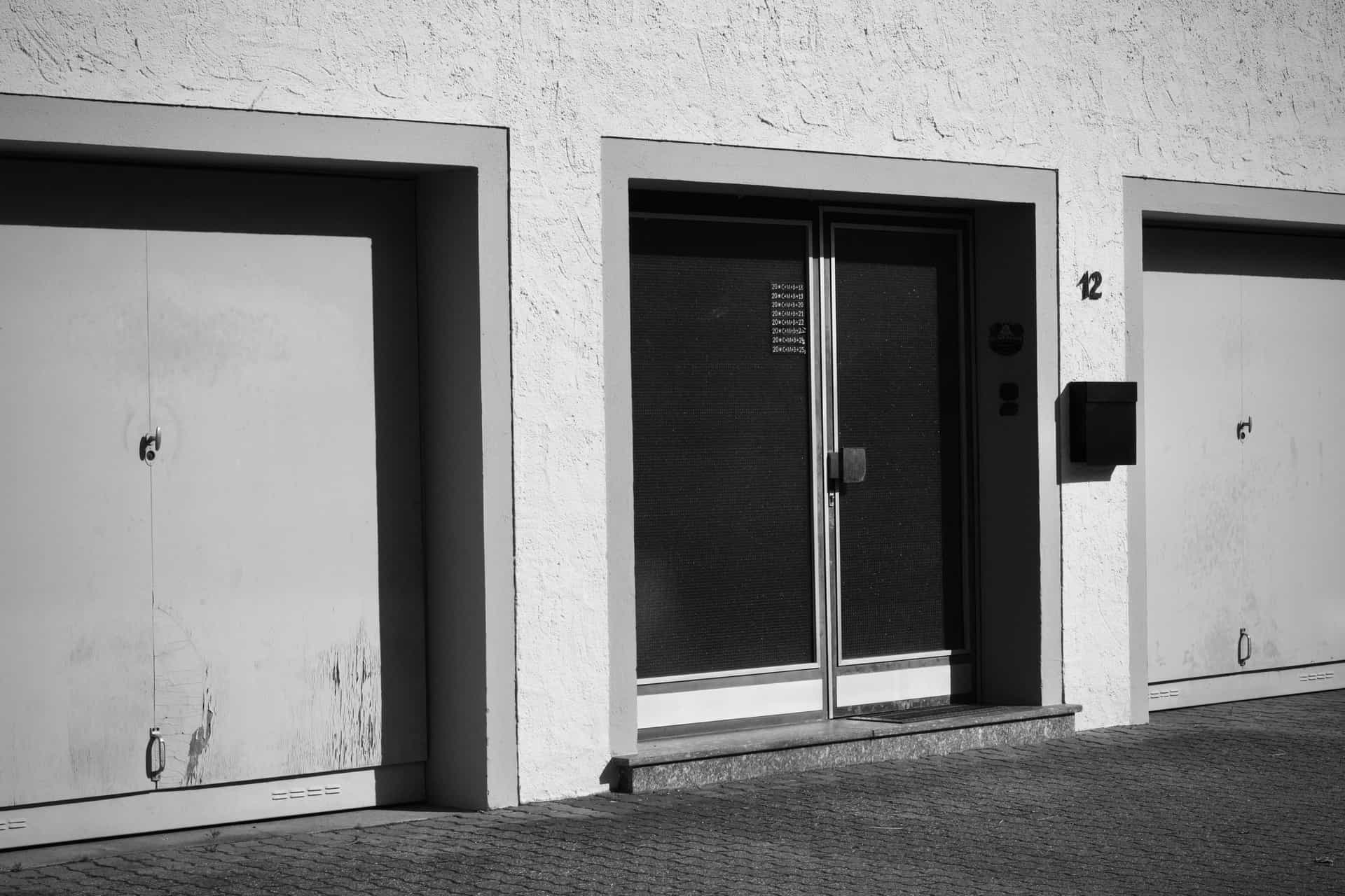 A sectional garage door closed onto a concrete slab with daylight visible along the bottom edge