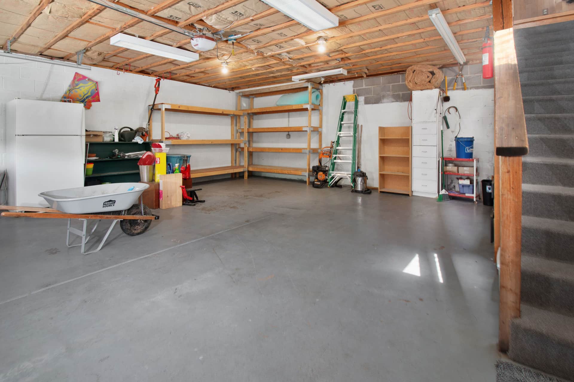 A garage interior with storage shelving and a concrete floor