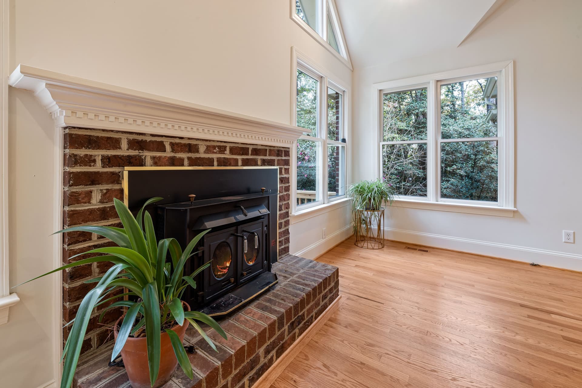 An unused fireplace in a room beside tall windows
