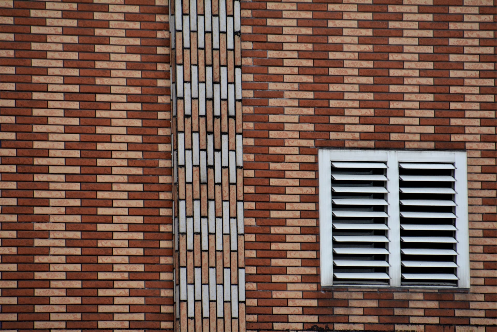 A brick foundation wall with a vent opening