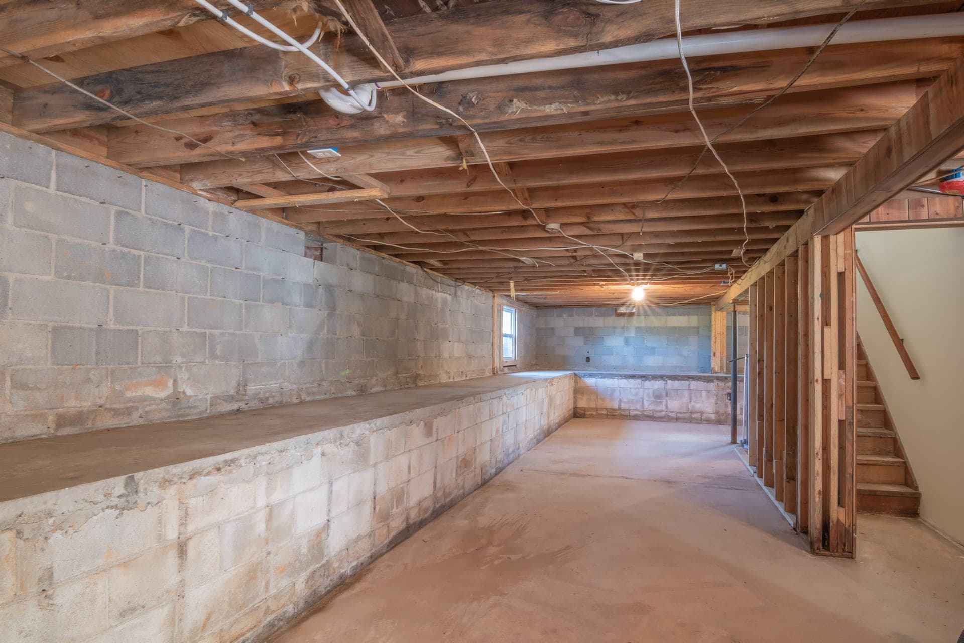 Exposed floor joists meeting a concrete block foundation wall in an unfinished basement