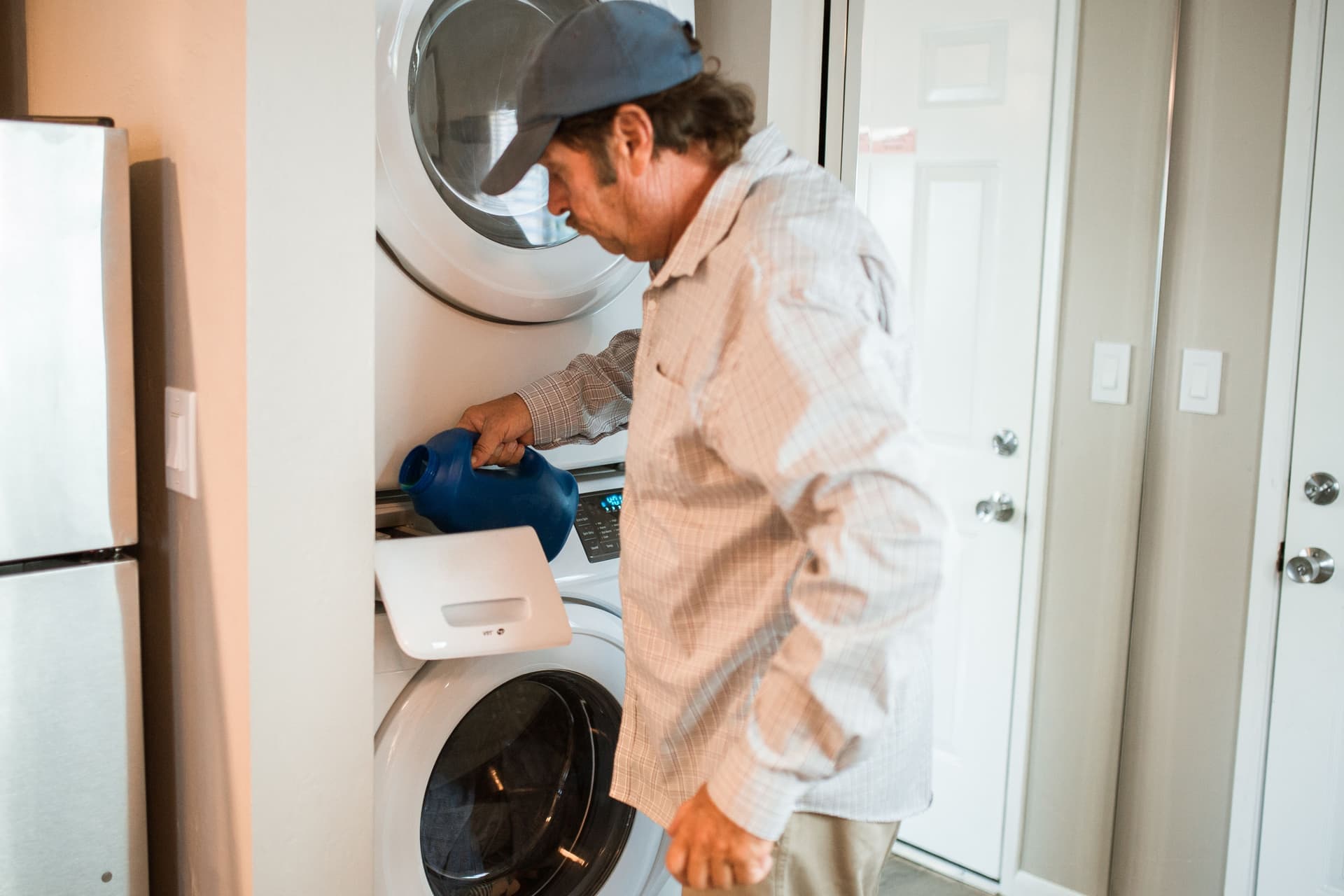 A person loading a washing machine in a laundry room