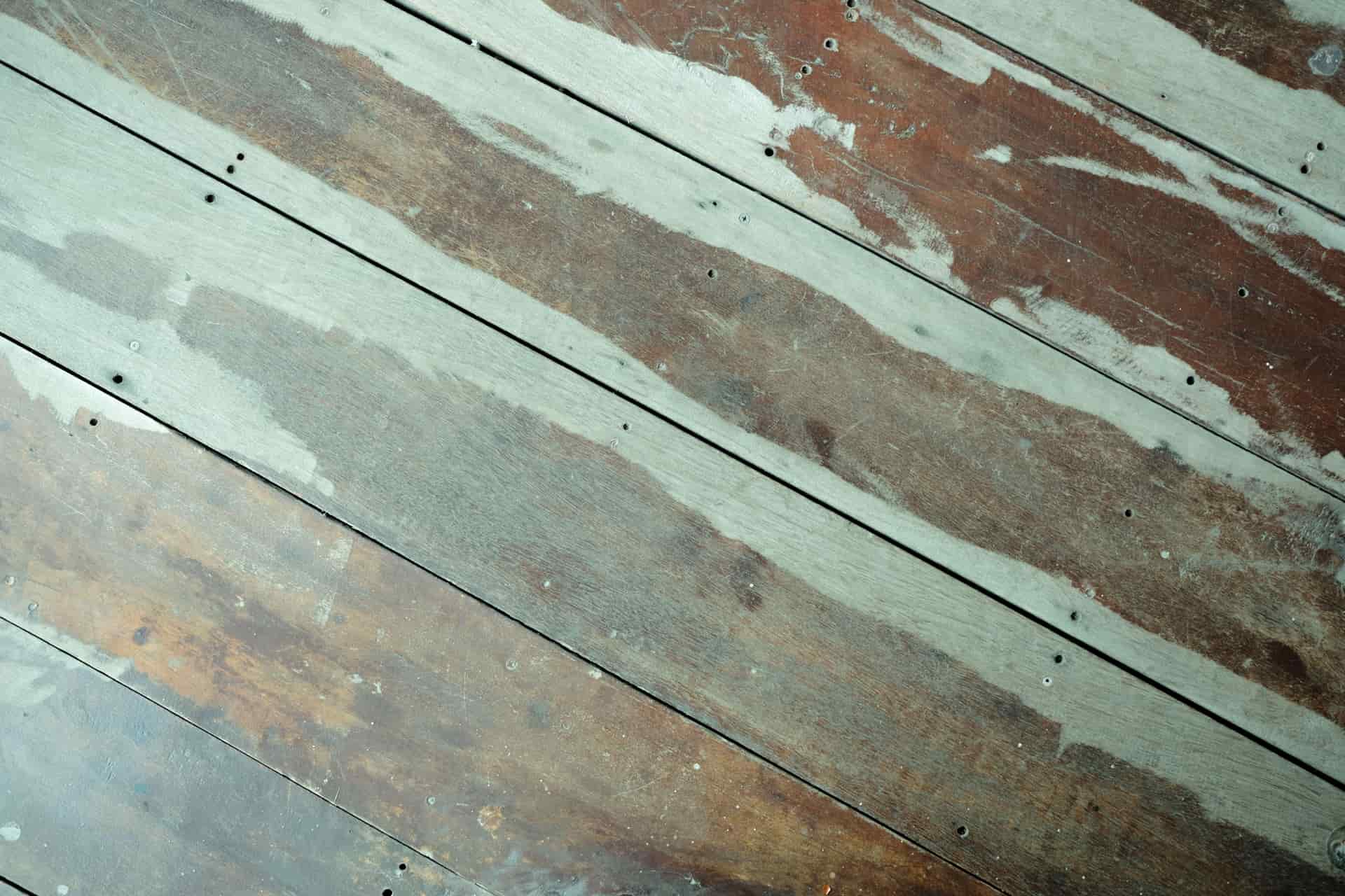 A close-up of old wooden floorboards with worn paint and visible gaps