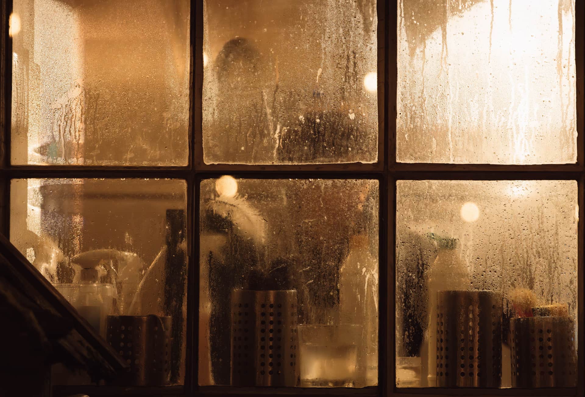 A warm room seen through a steamed-up window pane in winter