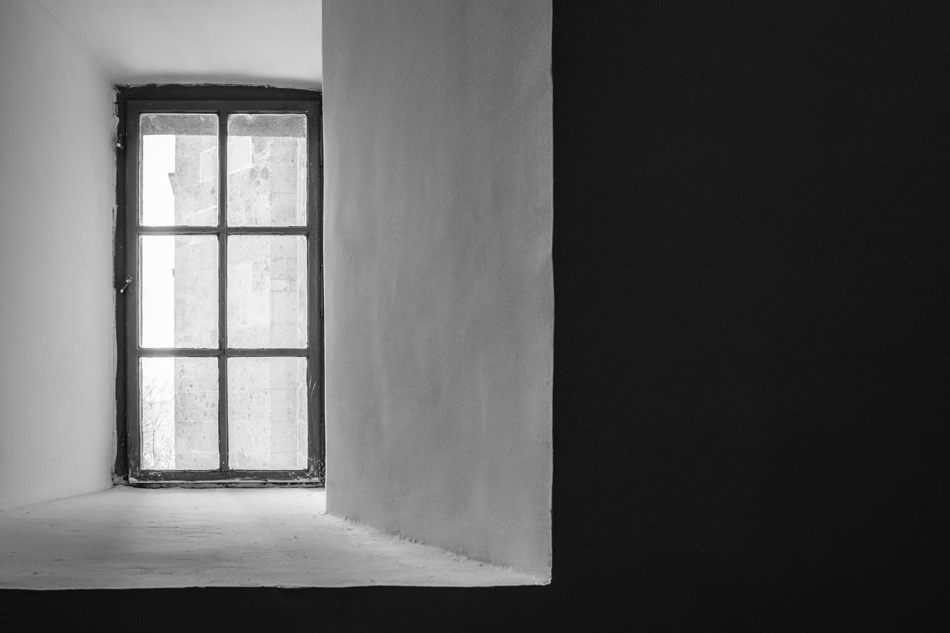 A side-hinged casement window with divided panes, set in a deep wall reveal