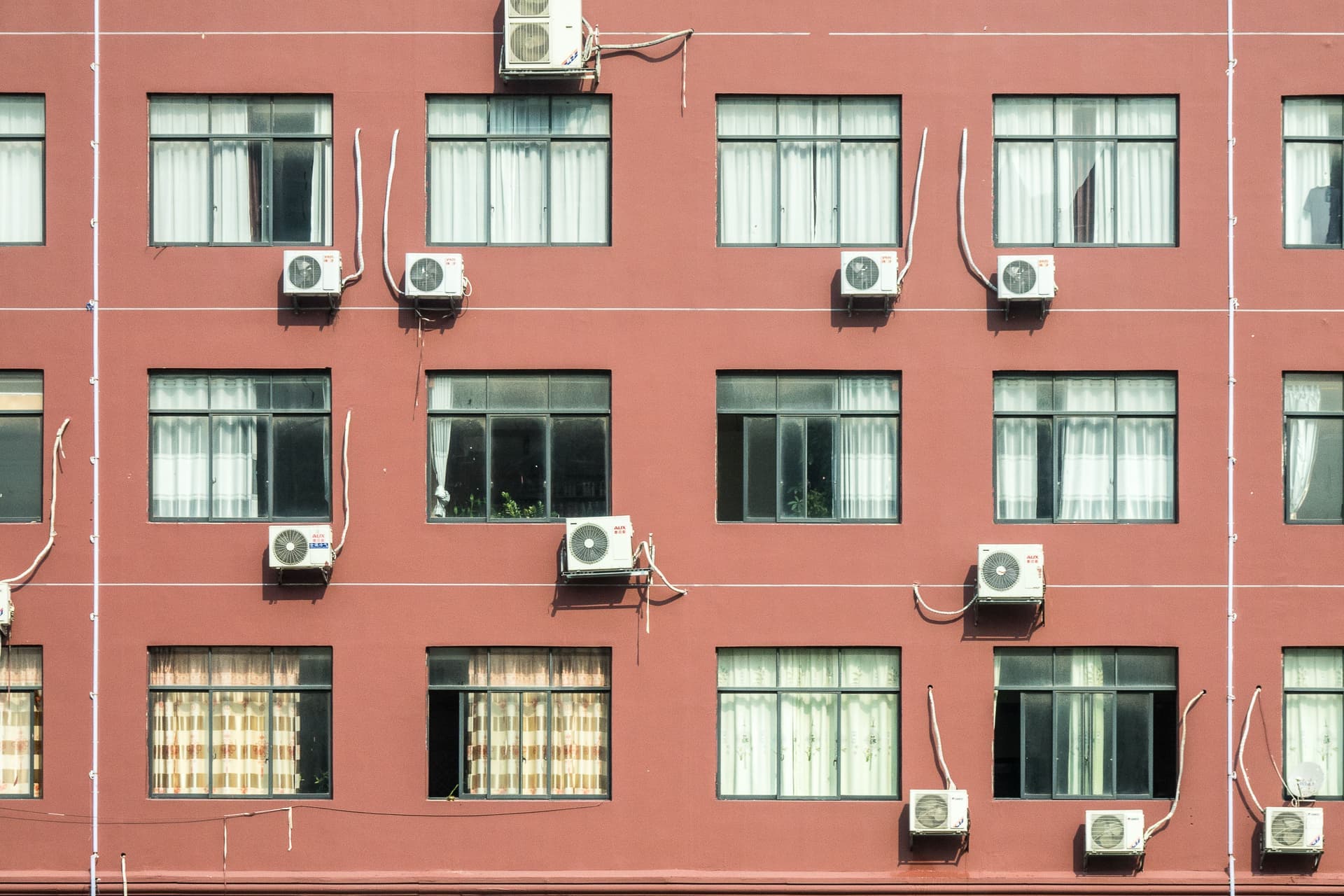 Air conditioning units mounted in the windows of an apartment wall