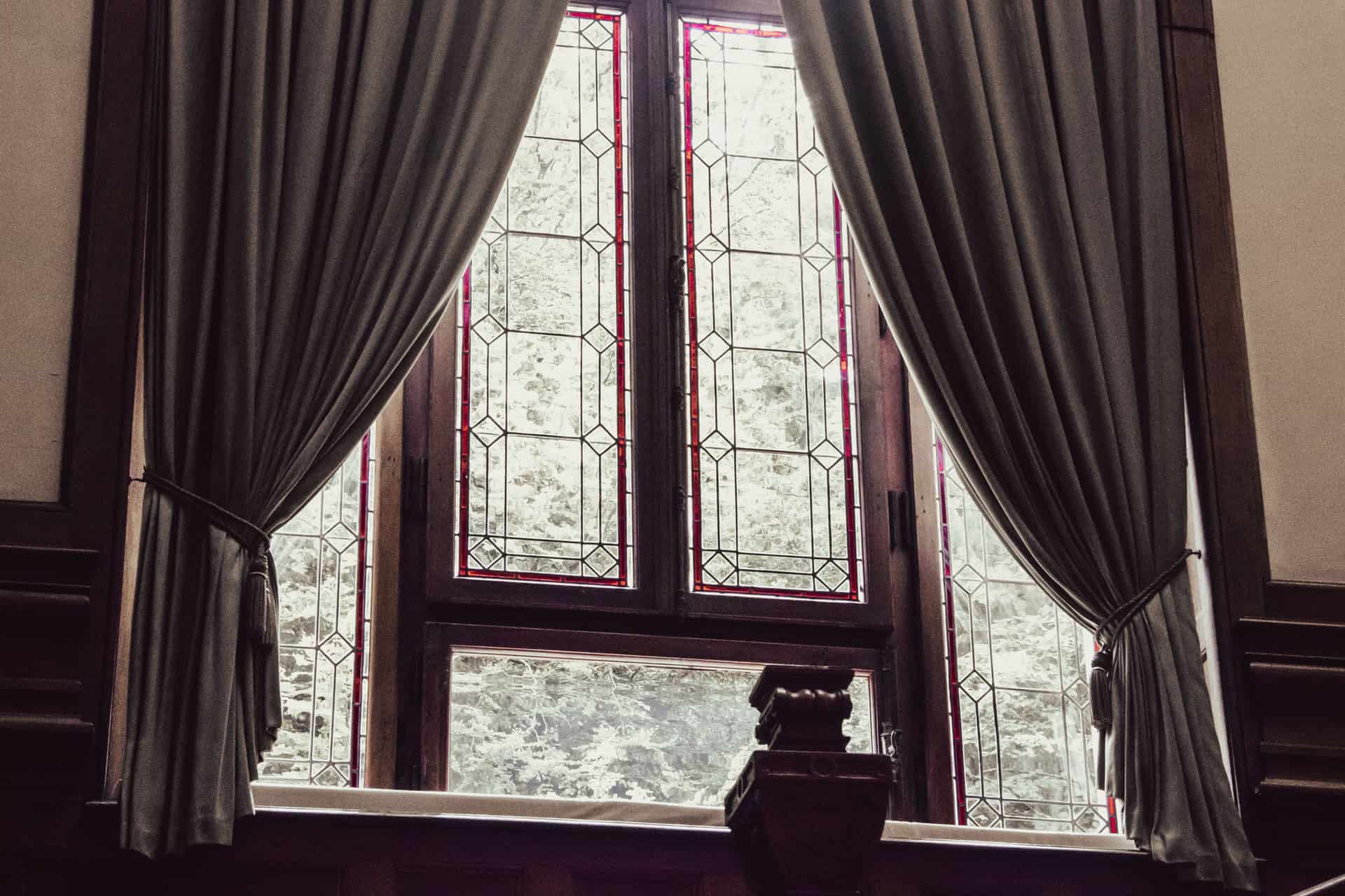 Self-adhesive weather stripping being applied along the lower sash of a double-hung window